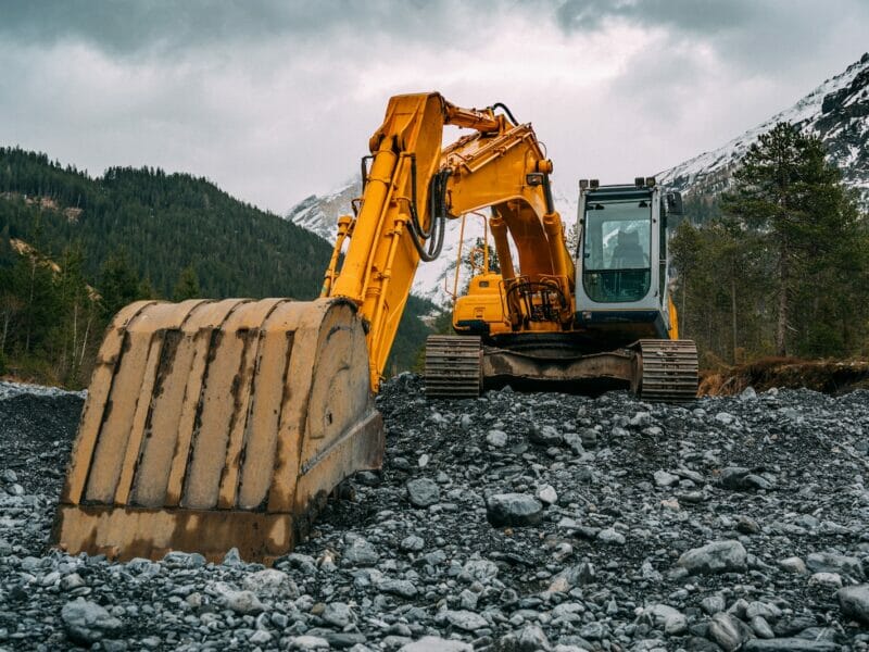 yellow and black excavator on rocky ground