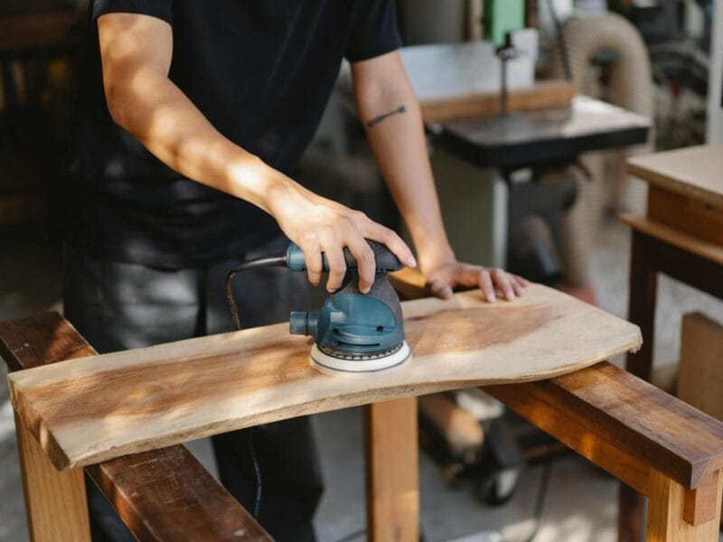 Craftsman polishing wooden board with grinding instrument