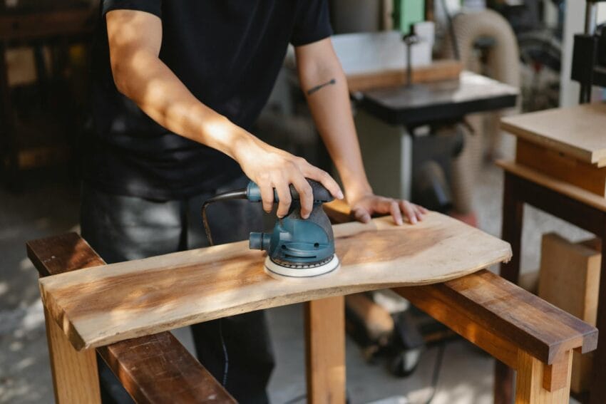 Craftsman polishing wooden board with grinding instrument