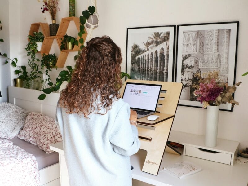 a woman standing in front of a desk with a laptop