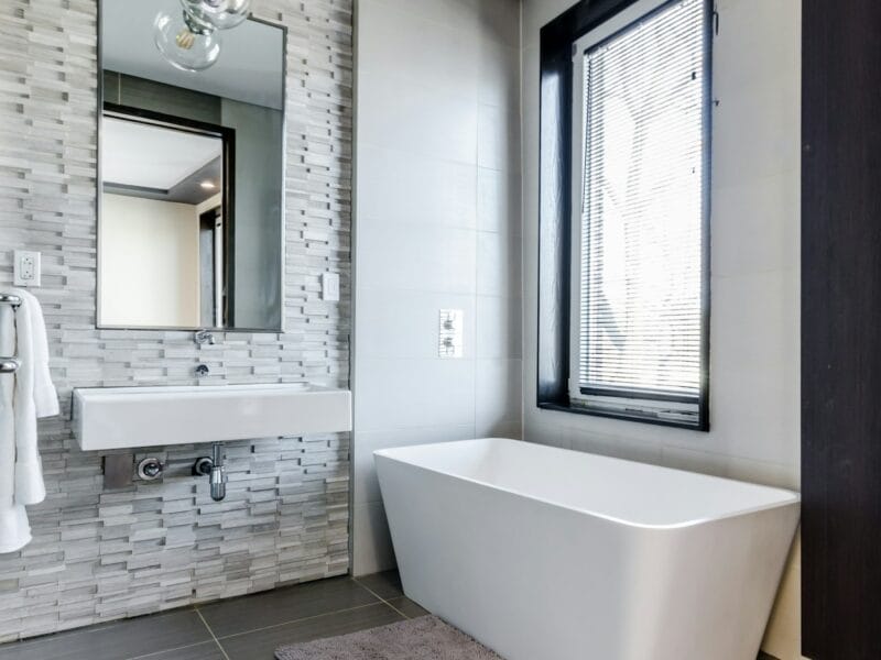 white ceramic bathtub near white framed window