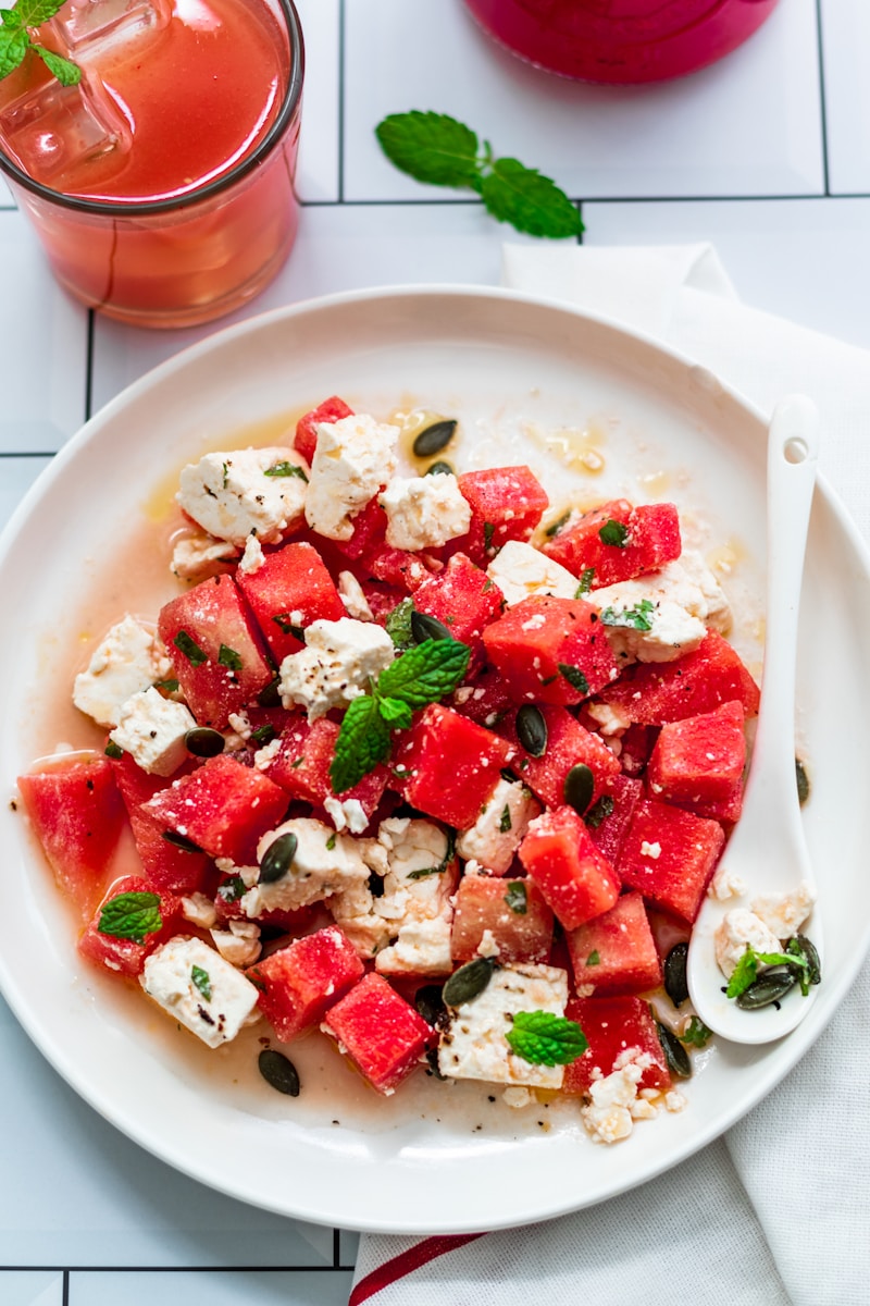 a plate of watermelon and feta salad next to a glass of water