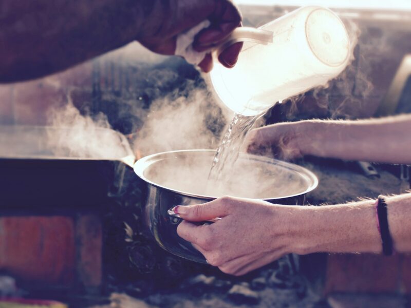 person pouring water on white ceramic mug