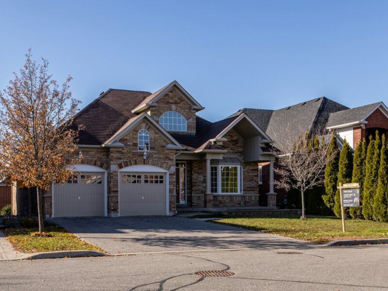 brown and white wooden house near green trees under blue sky during daytime