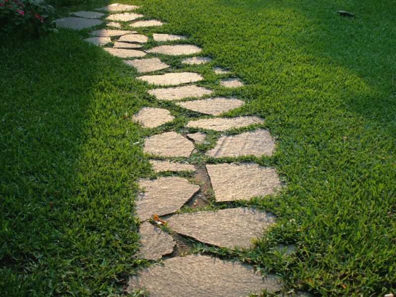 a stone path in the middle of a grassy area