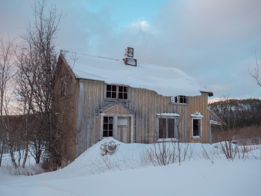 an old wooden house with snow on the ground