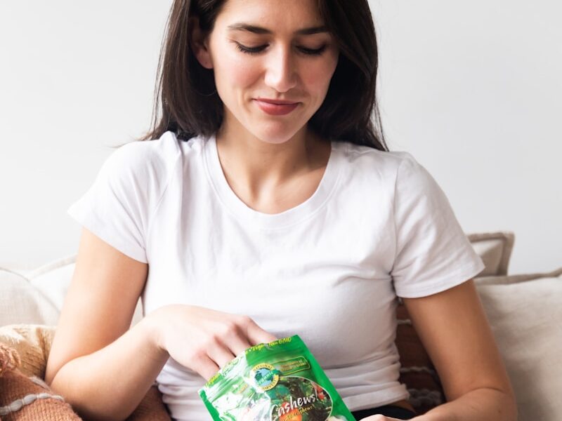 woman in white crew neck t-shirt holding green plastic pack