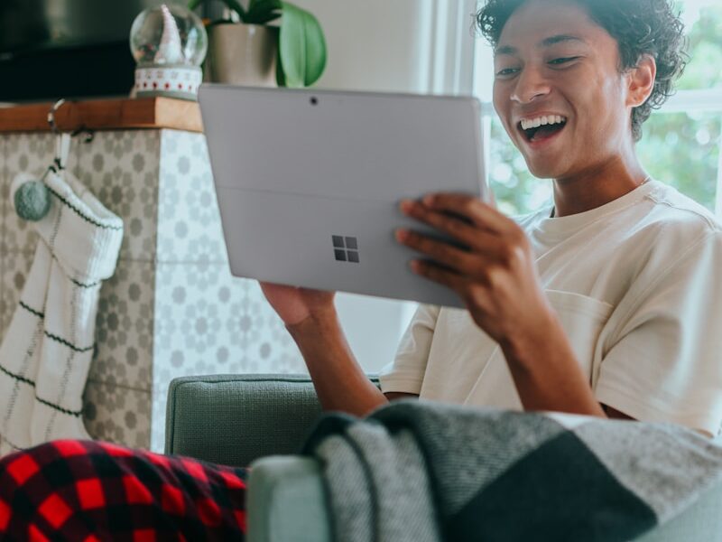 Man at home wearing pyjamas smiling at Surface Laptop screen