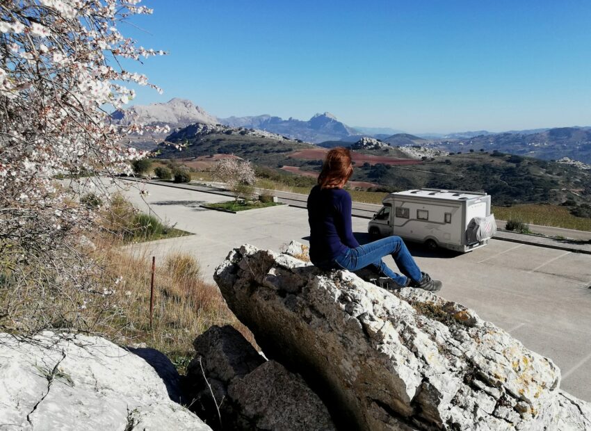 woman in black long sleeve shirt sitting on rock near body of water during daytime