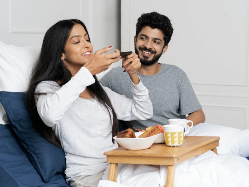 a man and woman sitting on a bed eating food
