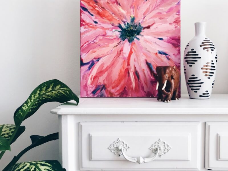 painting of pink flower on dresser near white vase