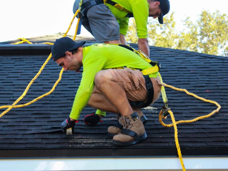 two men working on the roof of a house