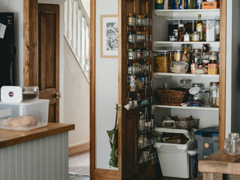 white plastic trash bin beside brown wooden shelf
