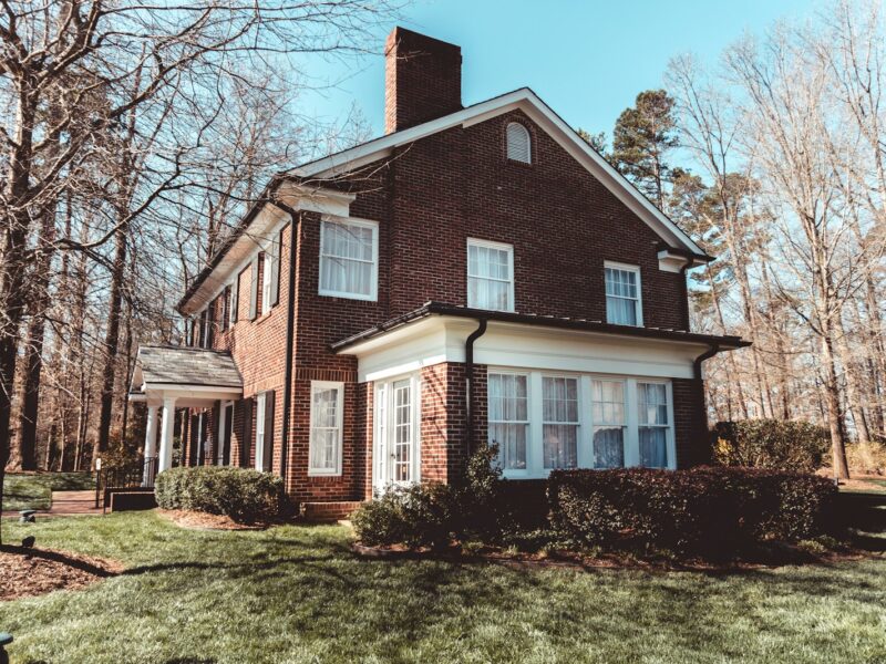 brown and white concrete house near bare trees under blue sky during daytime