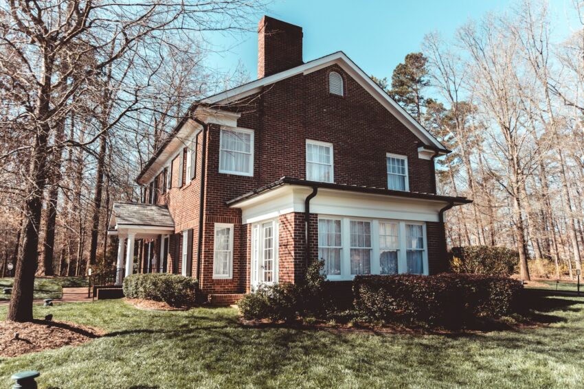 brown and white concrete house near bare trees under blue sky during daytime