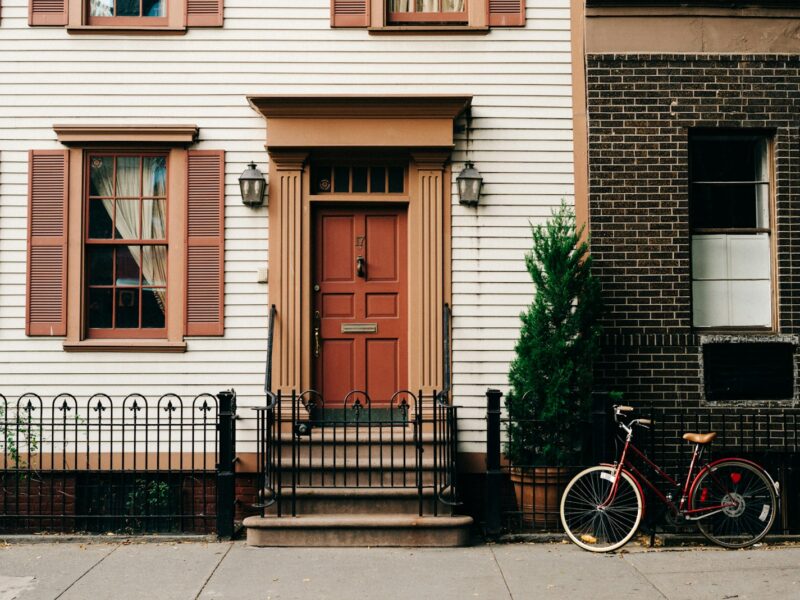 red bicycle parked beside black metal gate in front house