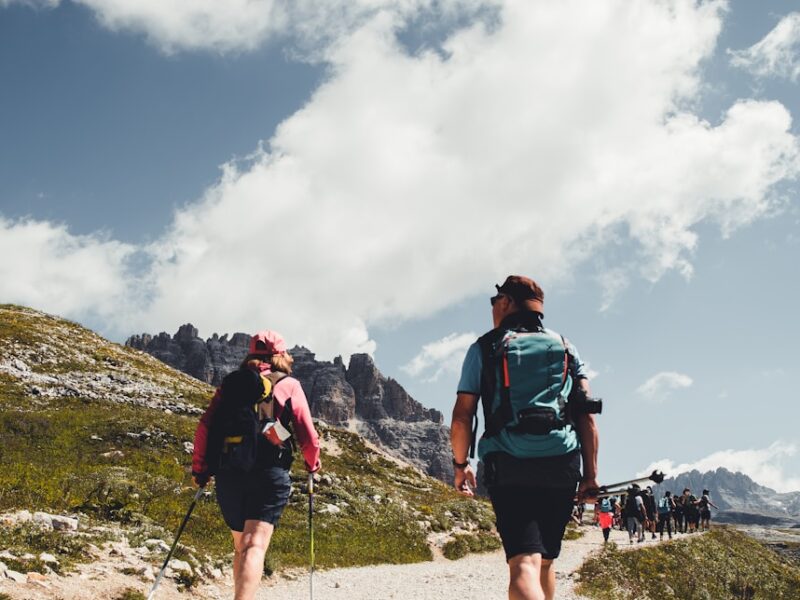 man in green shirt and black shorts with hiking backpack walking on gray sand during daytime