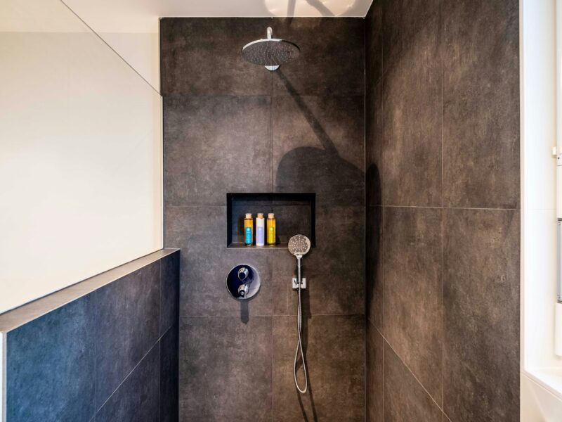 stainless steel shower head on white ceramic wall tiles