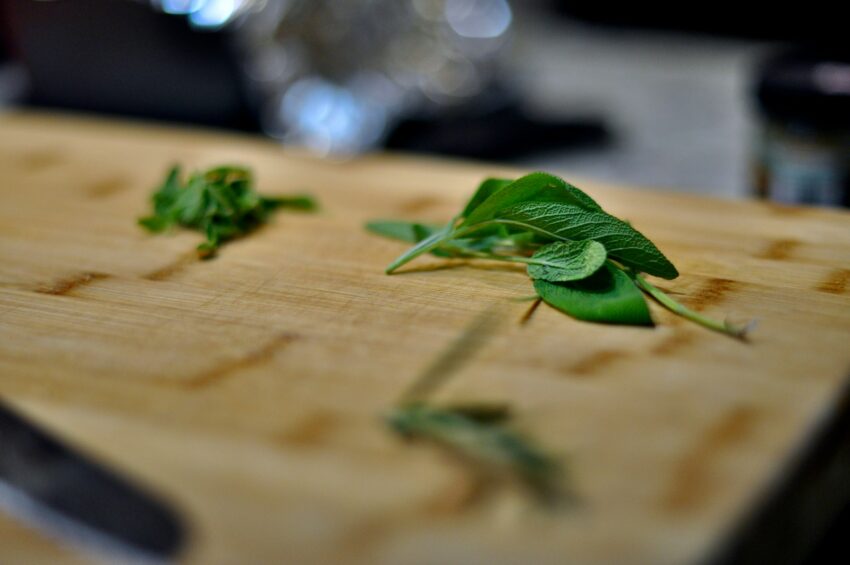 a cutting board topped with green leaves on top of a table