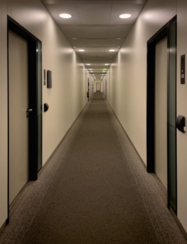 An empty hallway with doors stretches into the distance.