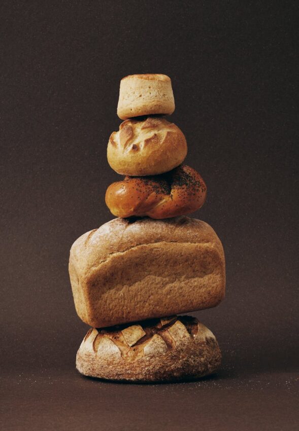 Stack of various bread loaves artfully arranged against a dark background.