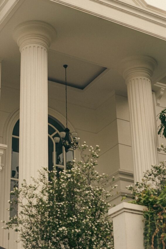 A white house with columns and a clock on the front of it