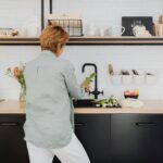 A woman standing at a kitchen counter preparing fresh vegetables. Modern and vibrant home interior.