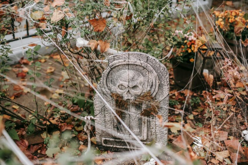 Decorative gravestone and cobwebs create a creepy Halloween atmosphere outdoors.