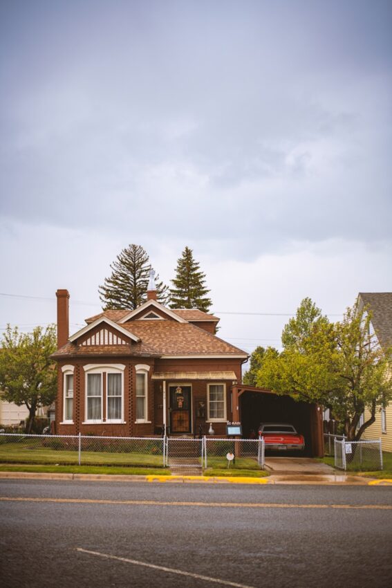 brown and white house near green trees under white sky during daytime