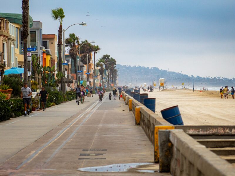 people walking on sidewalk near body of water during daytime