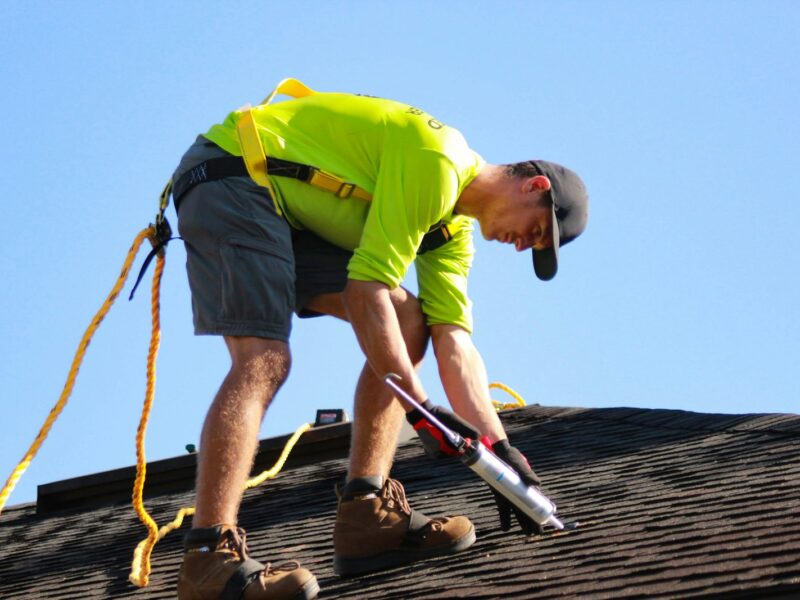 a man in a yellow shirt is working on a roof
