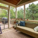 Relaxing screened porch with couch, plants, and outdoor greenery view.