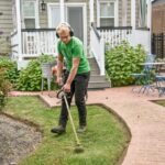 man in green t-shirt and black pants holding black and brown shovel