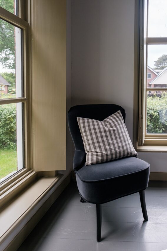 A dark chair sits next to two windows.