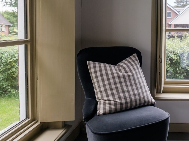 A dark chair sits next to two windows.