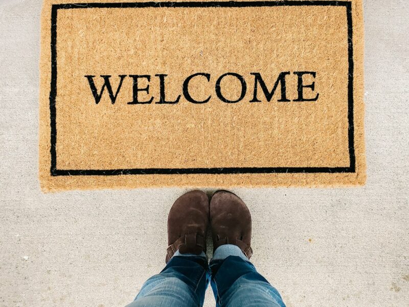 person in blue denim jeans standing on brown and black welcome area rug