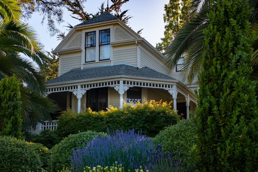 A beautiful Victorian-style house surrounded by a vibrant and lush garden.