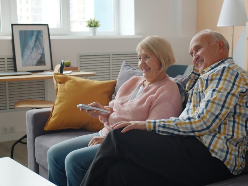 Elderly couple relaxing on a couch watching television