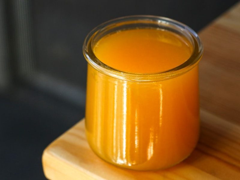 A glass of orange juice on wood.