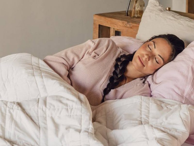 Woman peacefully sleeping on a cozy bed with soft bedding.