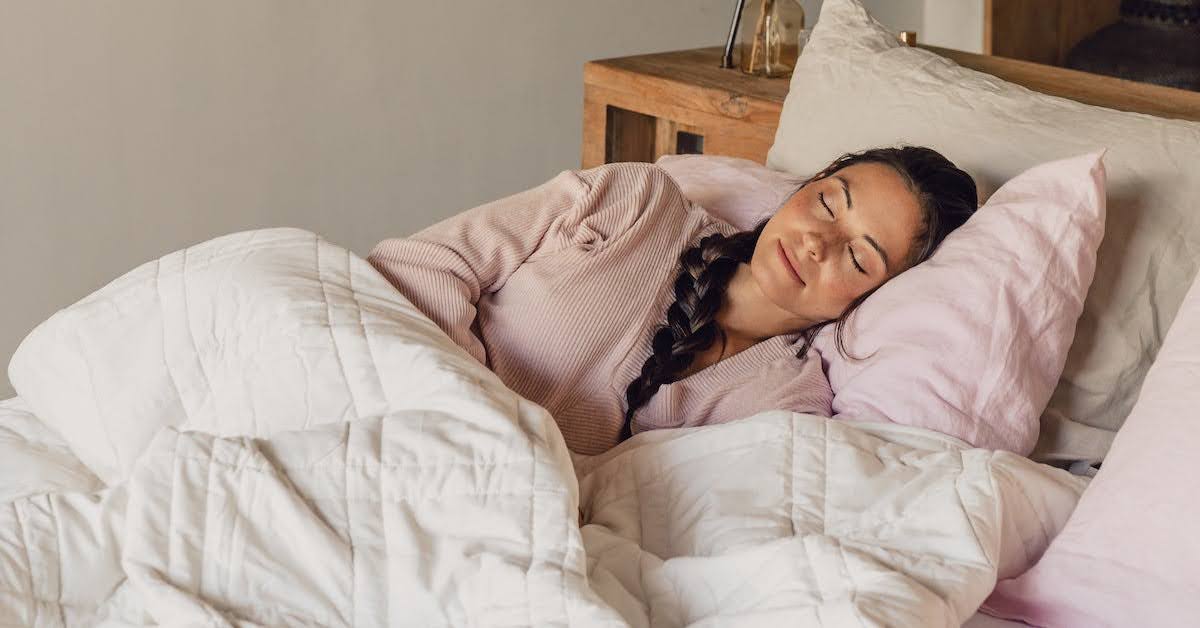 Woman peacefully sleeping on a cozy bed with soft bedding.