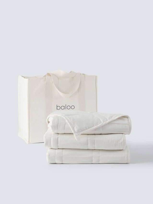 Neatly folded white quilts next to a labeled tote bag.