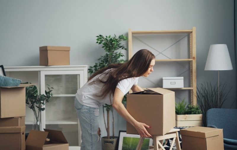 a woman moving boxes in a living room