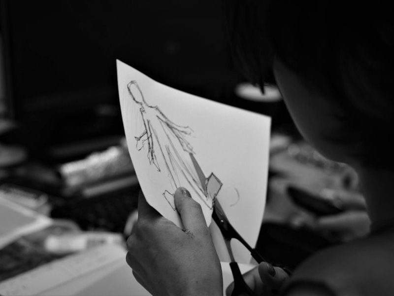 grayscale photo of woman holding pen writing on white paper