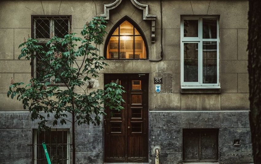 A weathered building facade with a large wooden door.