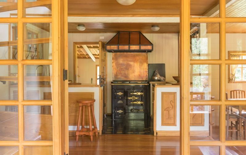 Warm rustic kitchen interior featuring a vintage stove and wooden furniture, offering a glimpse of nostalgic charm.
