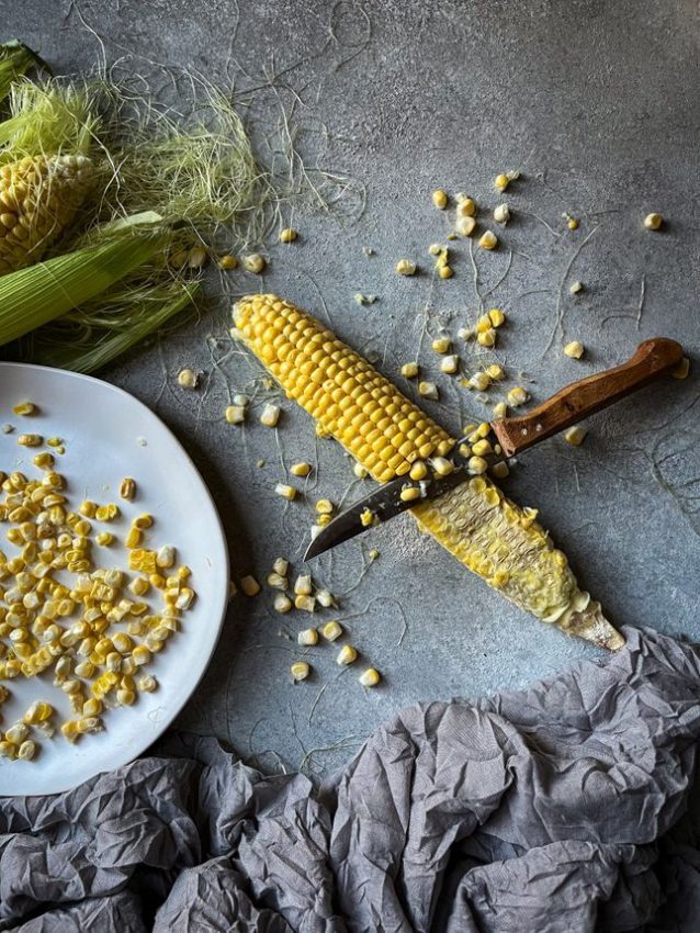 Close-up of a corn cob being sliced, evoking a warm autumn feel.