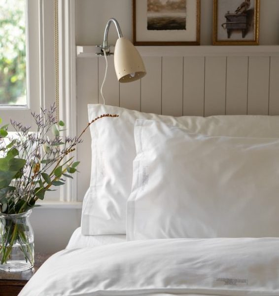 a bed with a white comforter and pillows