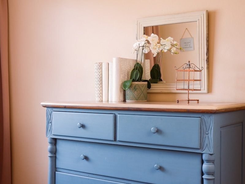 a blue dresser with flowers on top of it