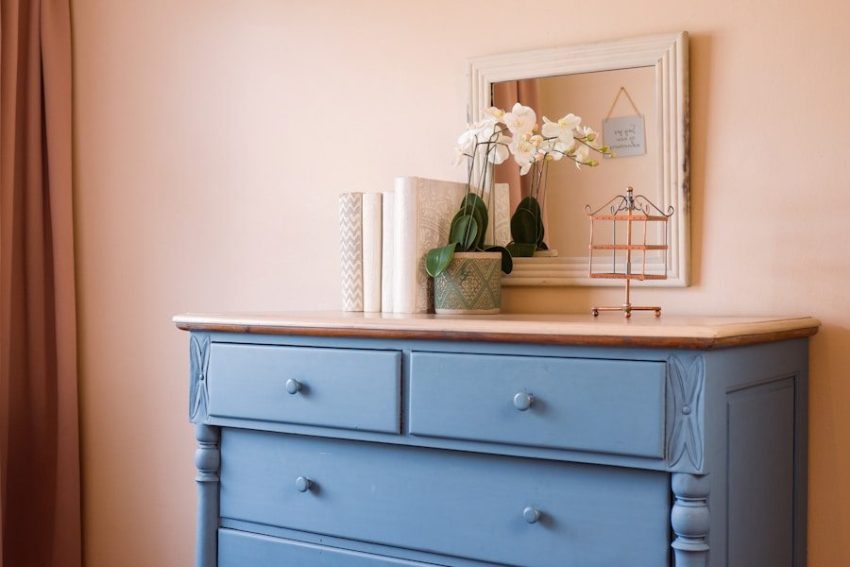 a blue dresser with flowers on top of it